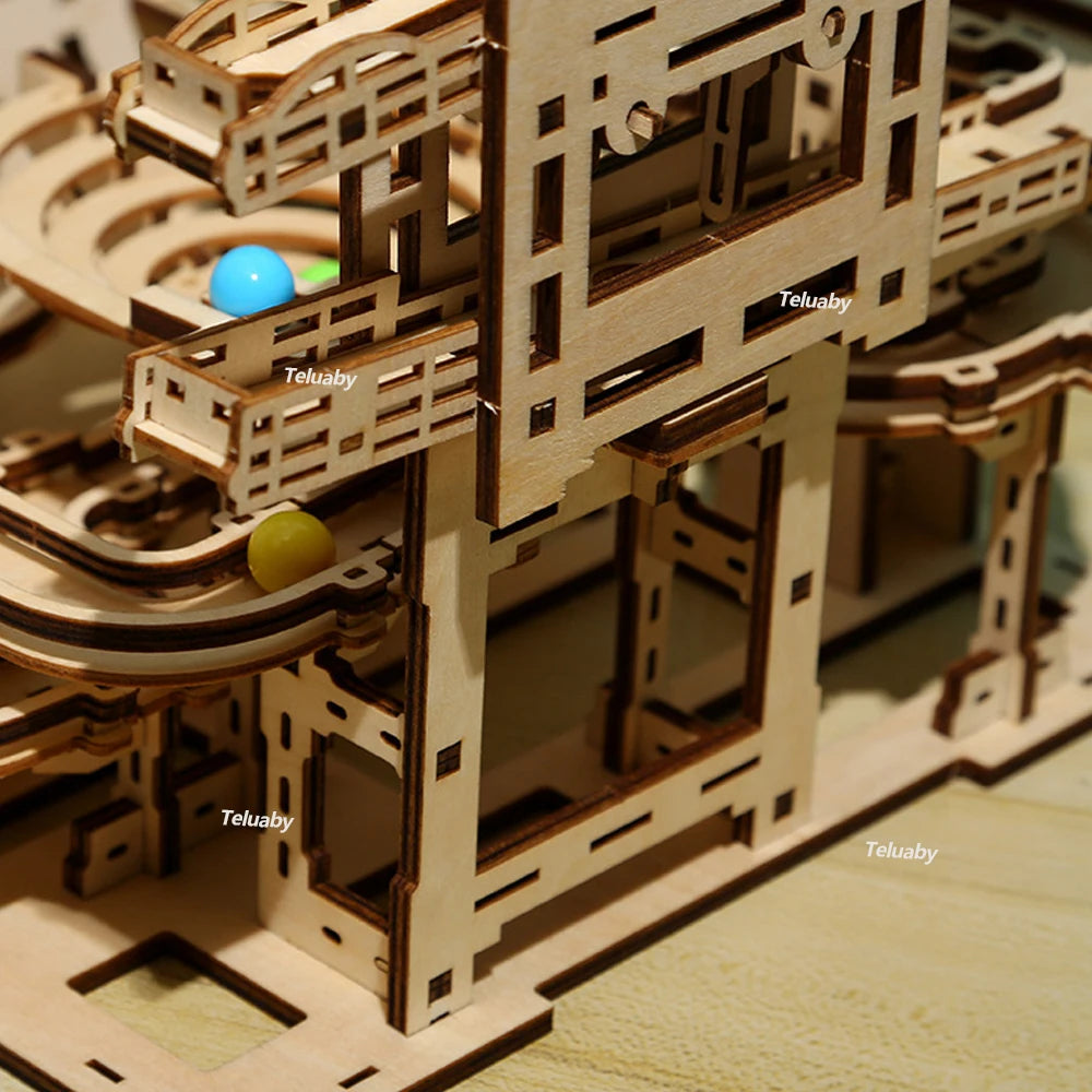 Two versions of Chriyungel mechanical marble runs: a large complex tower and a compact desktop version, both made of laser-cut wood with steel marbles.