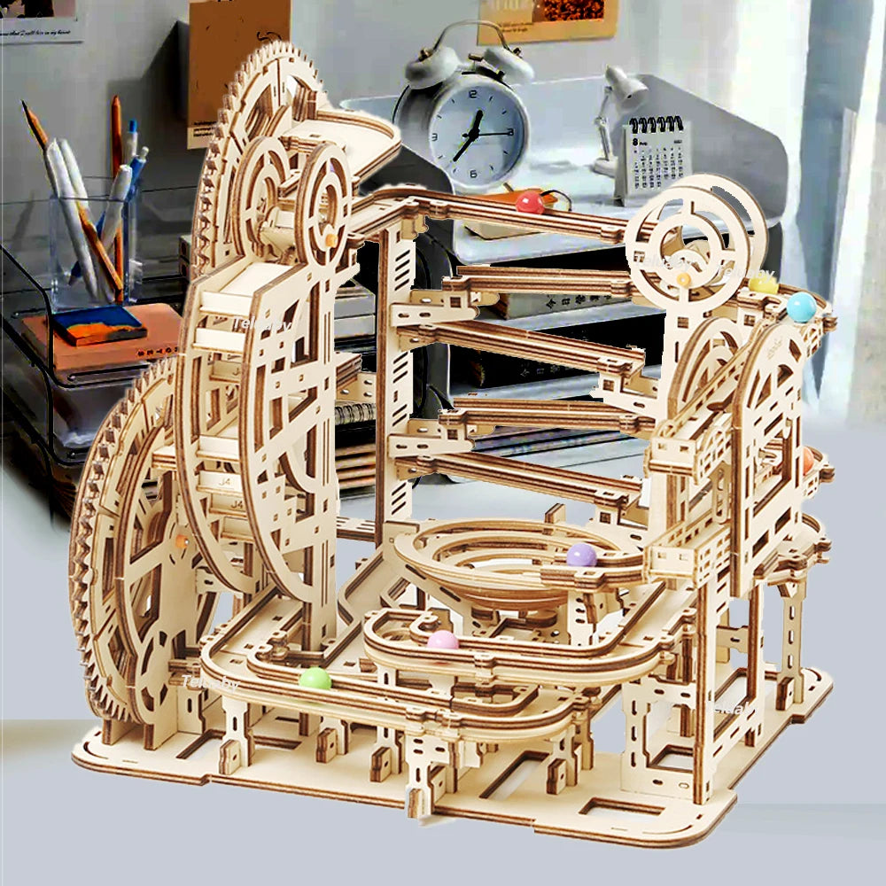 Two versions of Chriyungel mechanical marble runs: a large complex tower and a compact desktop version, both made of laser-cut wood with steel marbles.