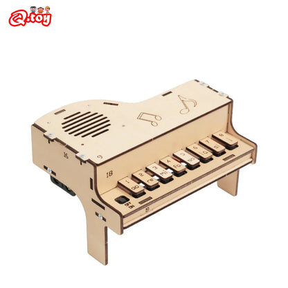 A partially assembled wooden electronic piano showing the internal circuitry, speaker, and wooden keys, emphasizing its educational and DIY nature.