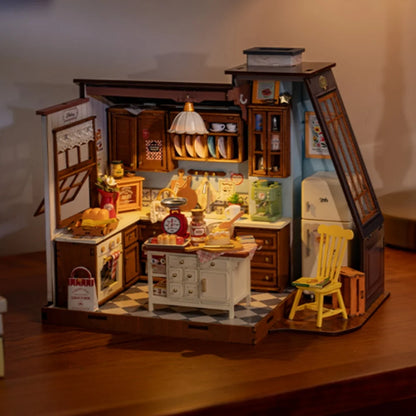 A fully assembled Rolife Baking Kitchen miniature house showing a vintage yellow chair, open oven with bread, and a glowing floral pendant lamp.